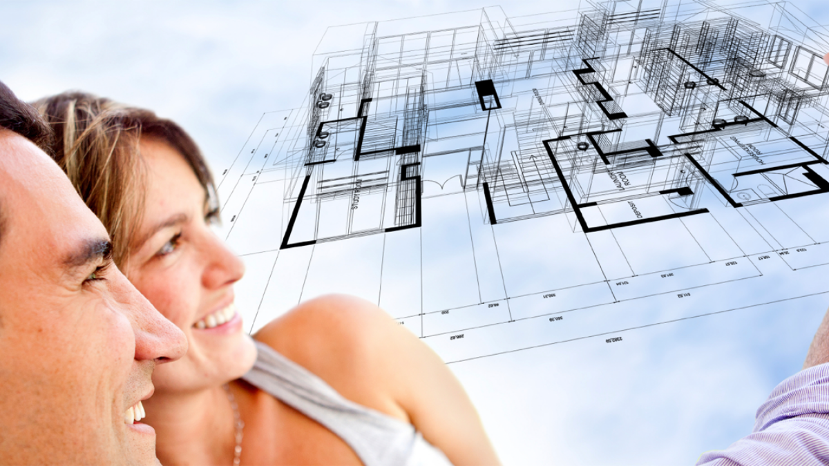 A smiling couple looking up at the floor plan of the home they are planning